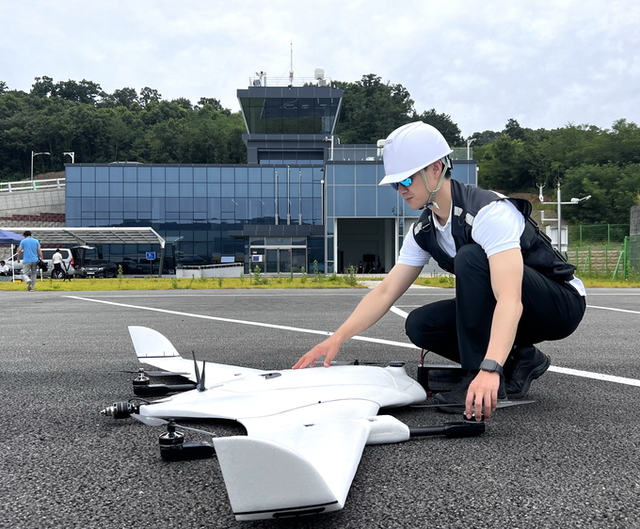 ▲ 의성군 드론 실증 현장에서 안전장비를 갖춘 연구원이 고정익 수직이착륙(VTOL) 무인기를 점검하고 있다. 의성군