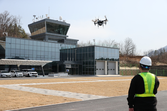 ▲ 경북 의성군 드론비행시험센터 전면 활주로에서 안전모와 형광 조끼를 착용한 조종자가 시계비행(LOS)으로 소형 쿼드콥터의 호버링 상태를 점검하고 있다. 의성군