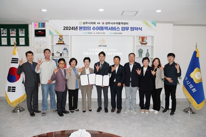 ▲ 상주시의회가 지난 2024년 6월 수어통역서비스 업무협약을 맺고 안경숙 의장(왼쪽·다섯번째), 시의원, 관계자 등이 기념 촬영하고 있다. 상주시의회 제공