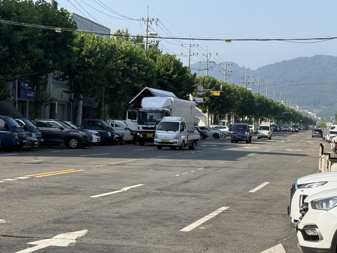 ▲ 1일 오전 대구도시철도 3호선 공단역에서 염색산업단지로 들어가는 왕복 6차로 도로에 불법주정차된 차량을 피해 차량이 통행하고 있다. 이유경 기자