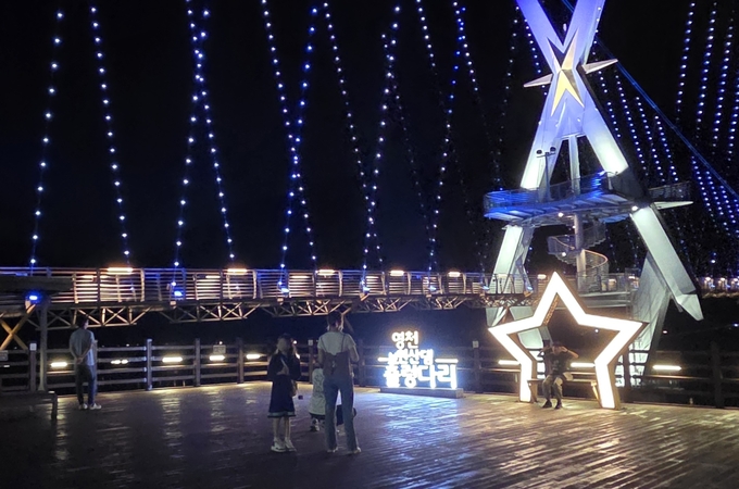 ▲ 4일 영천 보현산댐 출렁다리 야간 개장 첫날 가족단위 방문객이 출렁다리를 배경으로 포토존에서 기념촬영을 하고 있다. 권오석 기자