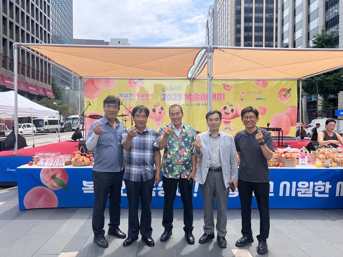 ▲ 조용일 금성농협 조합장(가운데)과 관계자들이 7월 30일 서울 청계광장에서 열린 ‘복숭아 데이’ 홍보행사에서 손가락 하트를 하며 소비 촉진 캠페인을 홍보하고 있다. 의성군 금성농협 제공