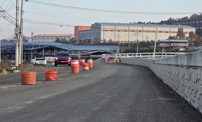 ▲ 13일 괴연마을 도로에 차량 추돌로 보이는 교통안전시설 PE드럼 사이로 차량들이 운행하고 있다. 권오석 기자