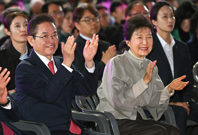 ▲ 박정희 대통령 탄신 108주년 숭모제례에 참석한 박근혜 전 대통령과 이철우 경북지사가 한자리에 앉아 박정희 전 대통령의 AI 복원 영상을 보고 난 후 박수를 치고 있다. 경북도 제공.