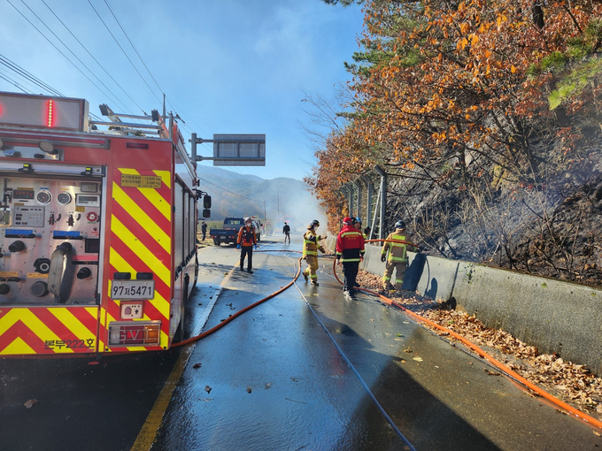 ▲ 19일 의성군 구천면 장국리 도로변에서 의성소방서와 대응 인력이 산비탈에 번진 화세를 차단하기 위해 소방펌프차를 전개한 뒤 갓길을 따라 집중 살수하며 연기를 정리하고 있다. 의성소방서