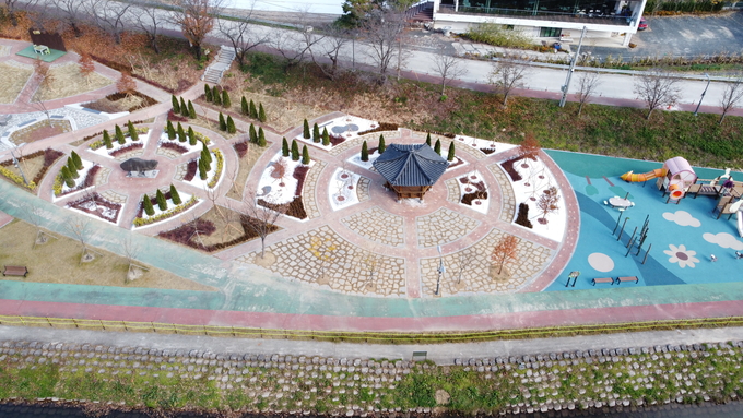 ▲ 경북 의성군 구봉공원 도시숲 내부를 상공에서 촬영한 모습으로, 정자와 반원형 화단, 어린이 놀이터가 남대천 산책로와 자연스럽게 연결되며 체류형 녹지 공간으로 재구성된 현장이 또렷하게 드러난다. 의성군